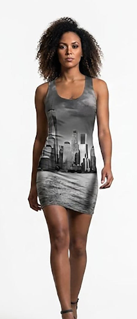 A woman modeling a sleeveless gray mini dress with a black and white city skyline graphic print, standing against a solid white studio background.