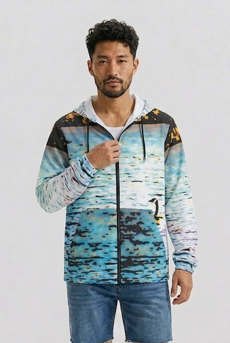 A man modeling a lightweight zip-up hoodie with a blue and white watercolor landscape print, paired with denim shorts and sandals, against a plain light gray background.