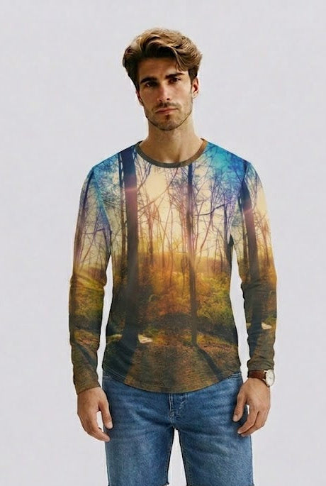 A man modeling a long-sleeve crewneck t-shirt with a colorful forest landscape print, paired with blue denim shorts and brown sandals, against a plain light gray background.